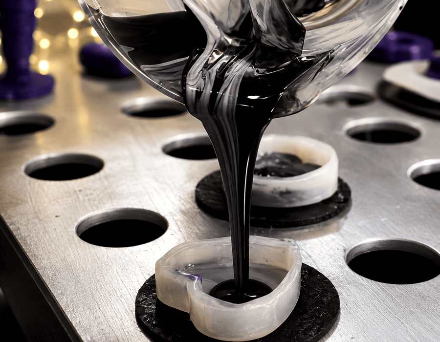 Black & white marble silicone being poured into Sh! silicone dildo moulds with heart-shaped bases.