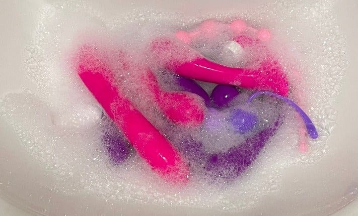 colourful sex toys in soapy water
