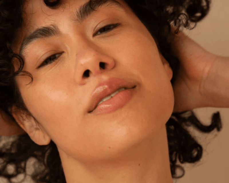 Close-up of a person with curly hair against a neutral background