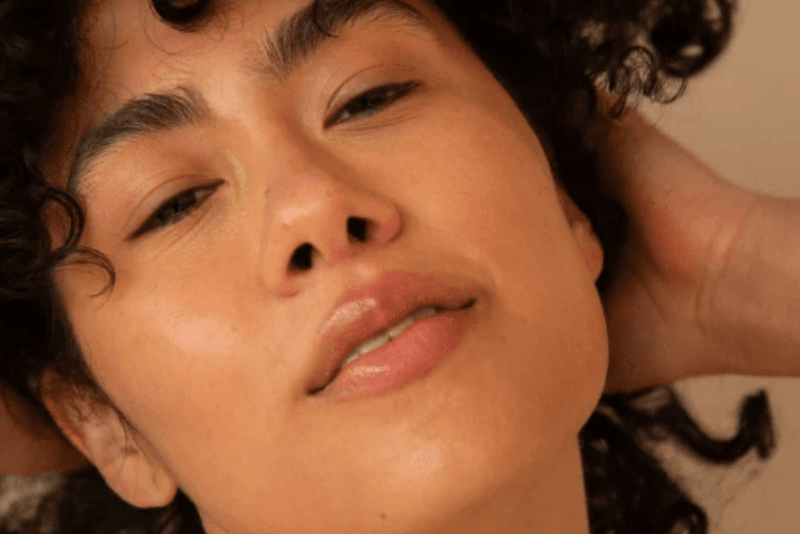 Close-up of a person with curly hair against a neutral background