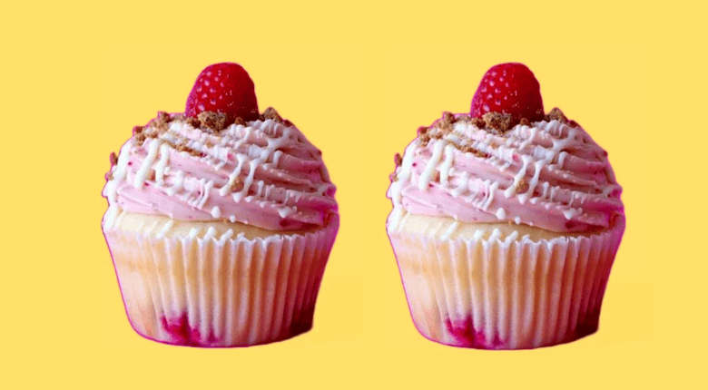 Two frosted cupcakes with pink icing, white drizzle, raspberry topping, and crumb garnish on a solid yellow background.