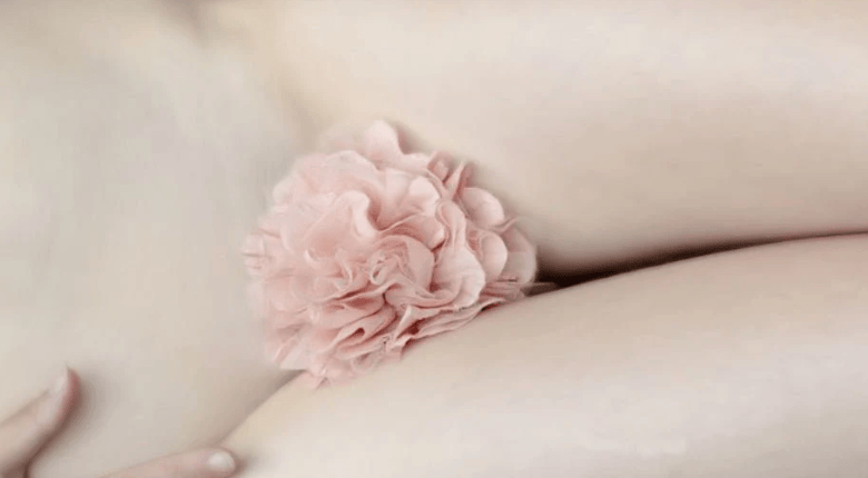 A pale pink flower worn on a person's woman's public area.