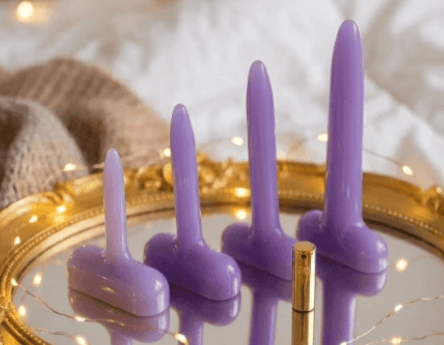 Sh! Purple silicone vaginal dilators on a gold tray with soft lighting and cozy background