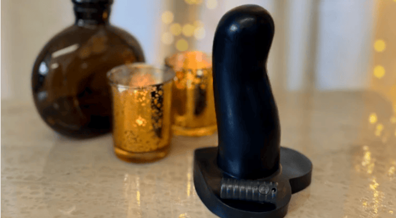 Vibrating Honey Silicone Dildo on a refective table with gold tea lights & black perfume bottle.